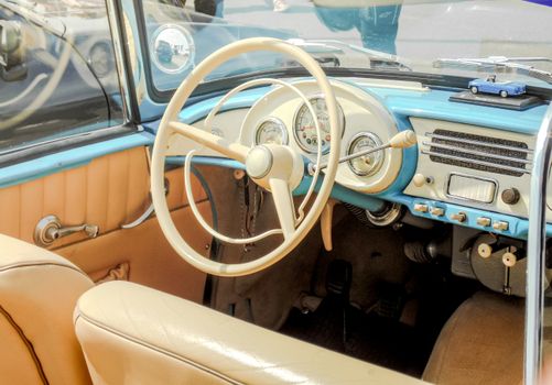 A vintage car's interior showcasing a classic steering wheel, dashboard, and retro details.