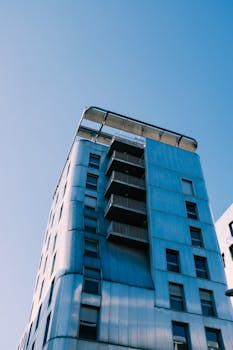 在清澈的蓝天下，一座引人注目的现代建筑以其独特的立面被低角度拍摄