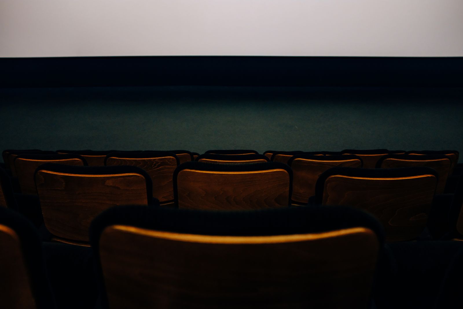 Rows of plain timber seats facing a blank wall