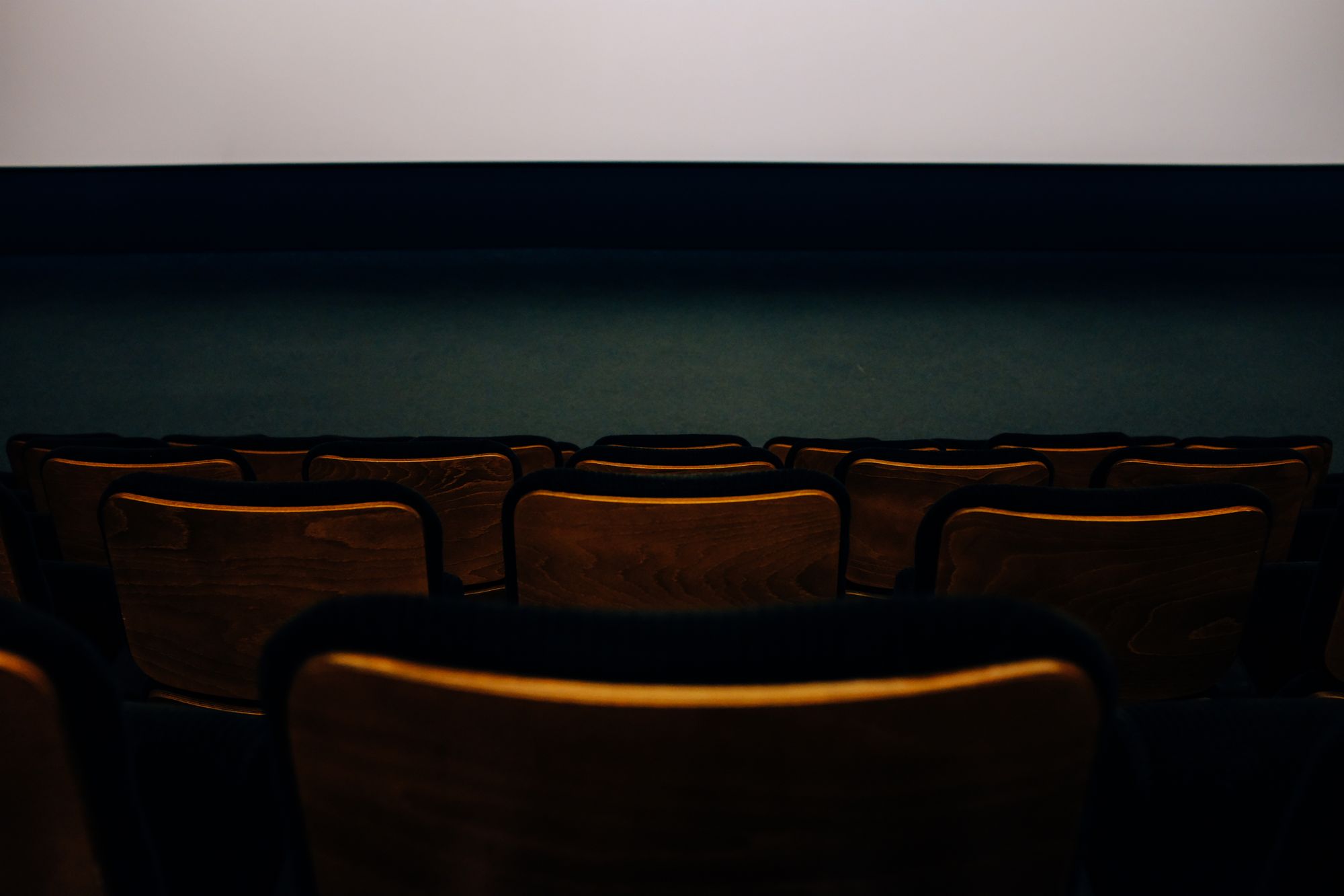 Sala de cine a oscuras con las butacas vacías frente a la pantalla iluminada