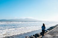 一个人享受宁静的海滩景色，在晴朗的蓝天下观看海浪