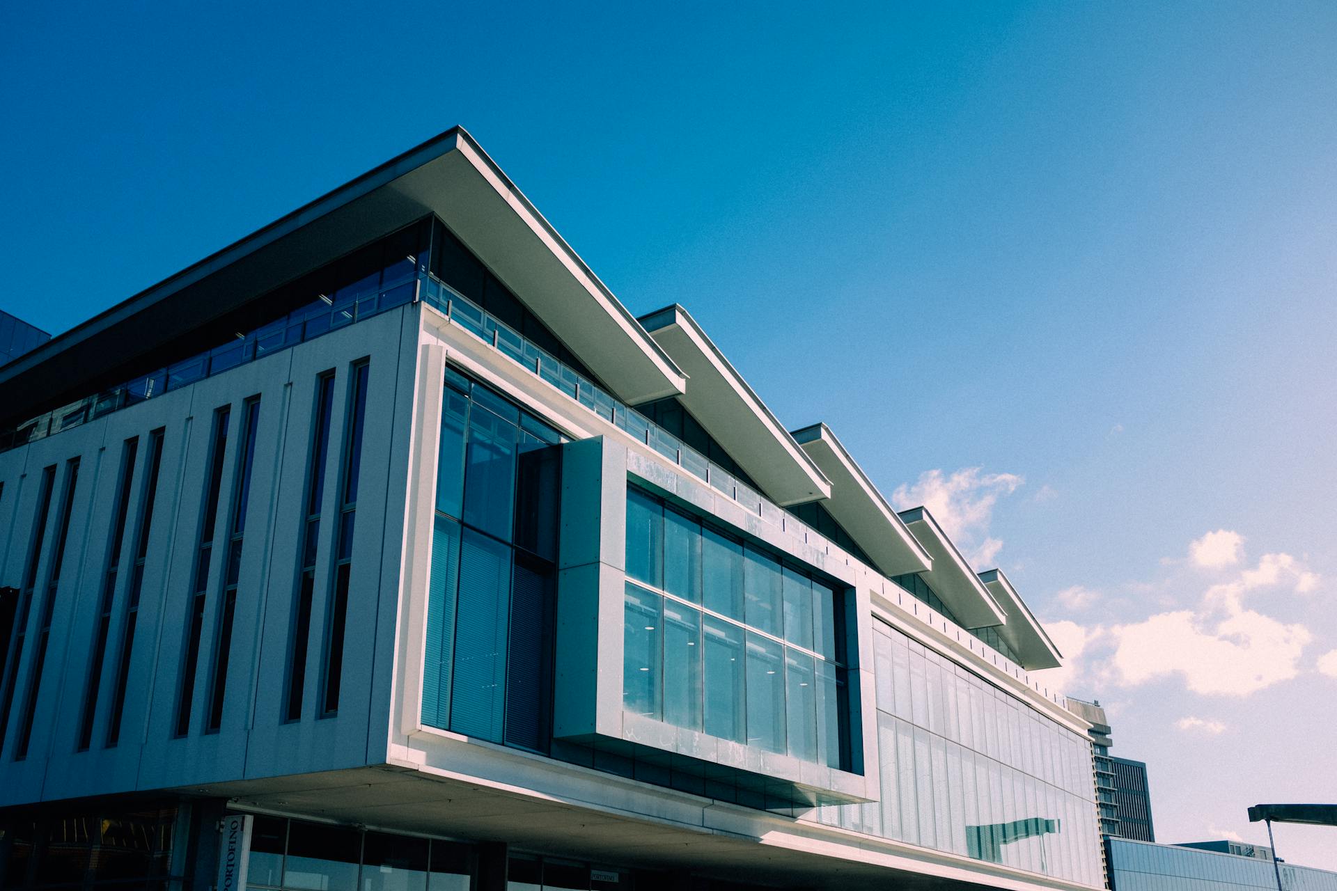 Low angle view of a modern building with a glass facade against a clear blue sky.