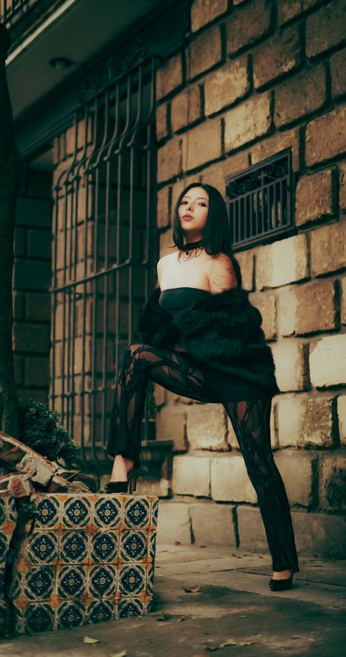 Free Chic fashion model posing in an urban setting, exuding elegance and confidence against a rustic backdrop. Stock Photo