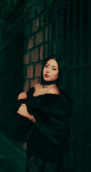 Stylish woman in black outfit posing against urban backdrop, exuding elegance and confidence.