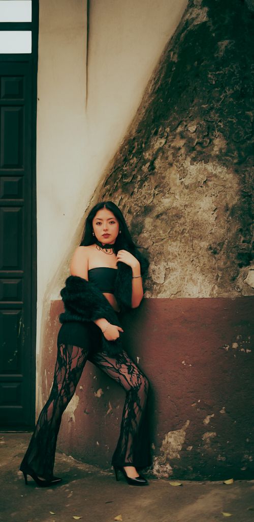 Free Glamorous woman in fashionable attire poses confidently against an aged wall, exuding elegance and style. Stock Photo