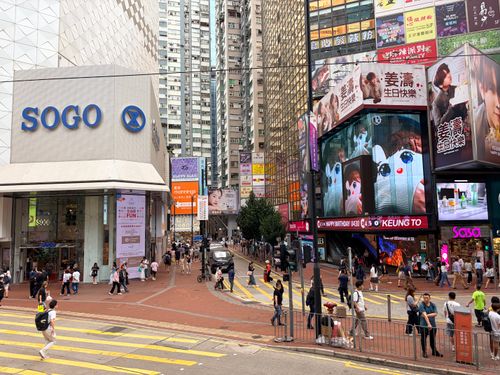 Free Vibrant city scene depicting a busy street near Sogo Department Store in Hong Kong, with digital billboards and pedestrians. Stock Photo