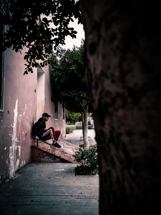 Man Sitting on Concrete Stairs In Narrow Road