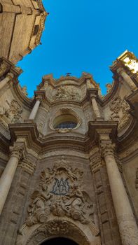 Stunning Baroque architecture of a cathedral facade in València, under a vibrant blue sky.