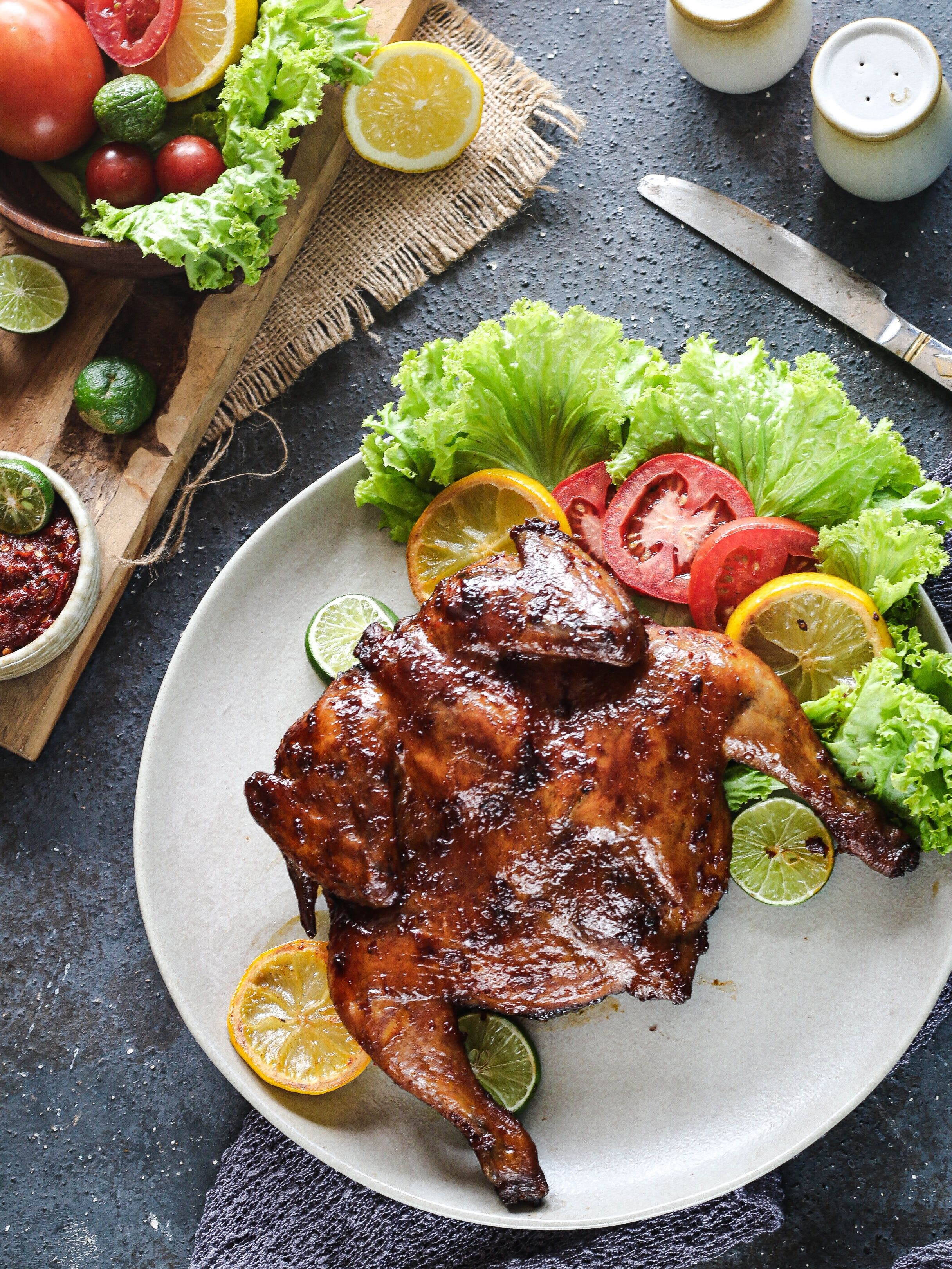 Delicious roasted chicken garnished with fresh vegetables and citrus slices on a plate.