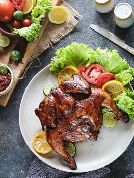 Delicious roasted chicken garnished with fresh vegetables and citrus slices on a plate.