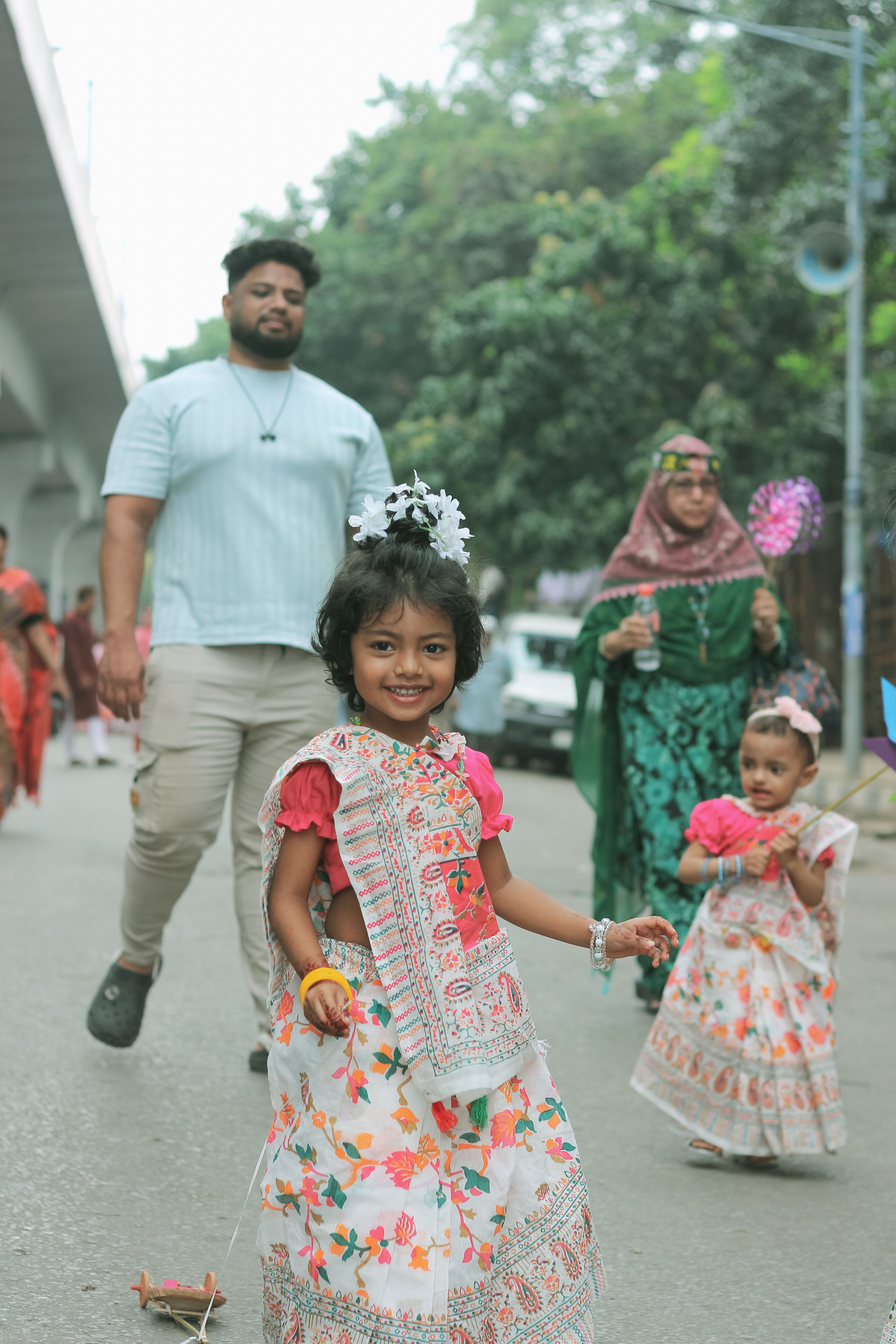 Children in traditional attire celebrating at a vibrant street festival in Dhaka, Bangladesh.