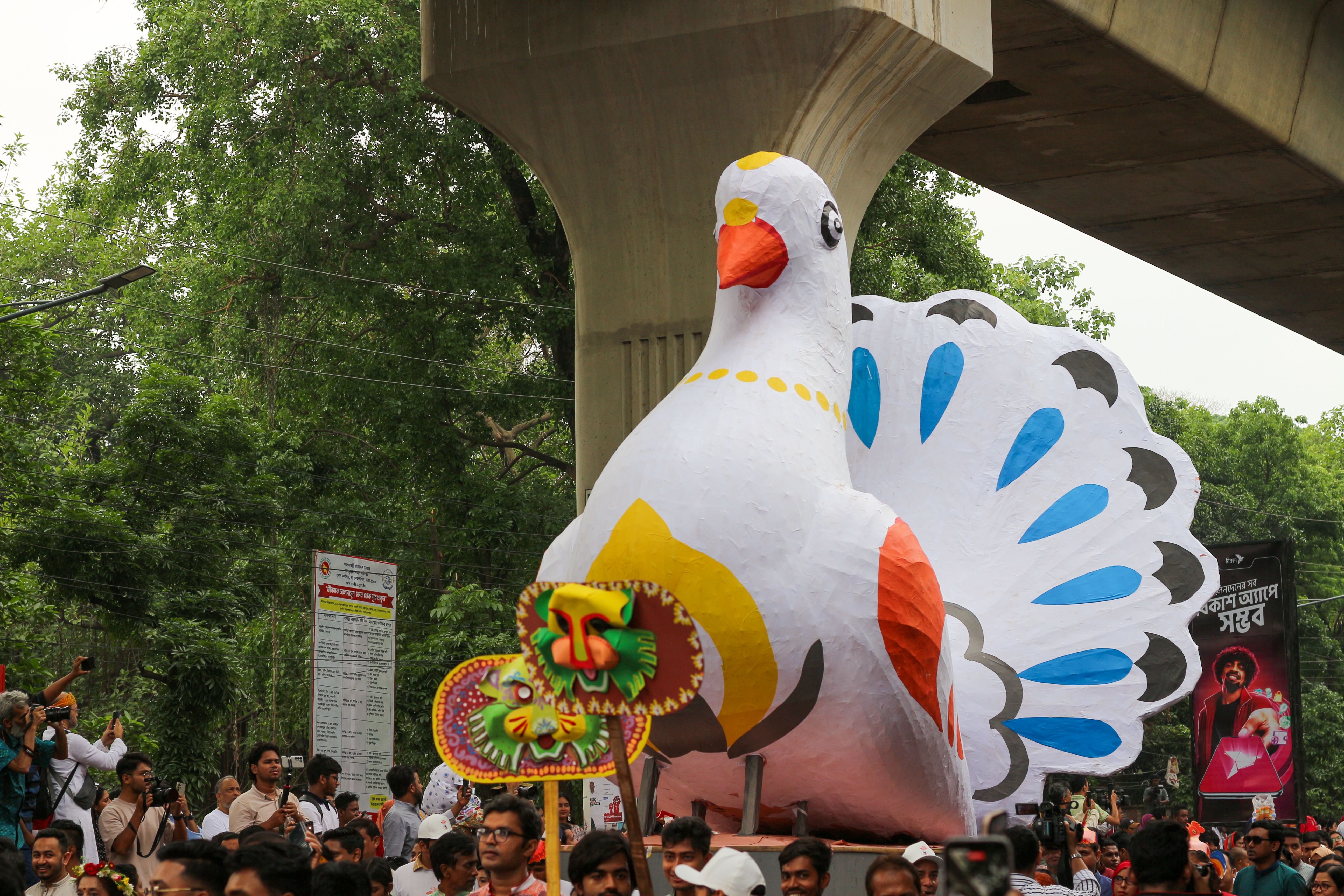 Vibrant celebration in Dhaka featuring a colorful bird float in a festive procession.