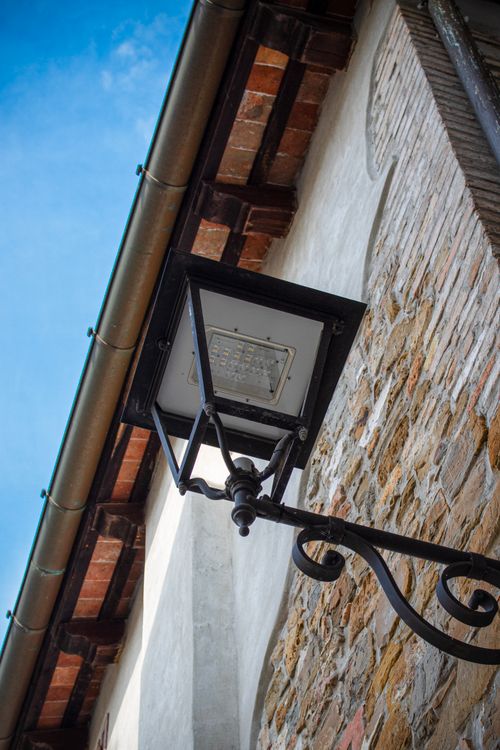 Free Rustic streetlamp on a historic building in Grado, Italy, under a clear blue sky. Stock Photo