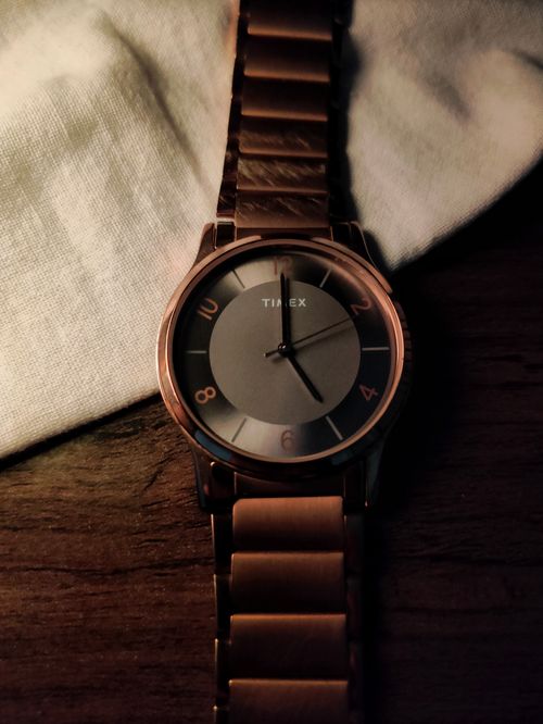 Free Stylish rose gold wristwatch with a sleek design, placed on a dark wooden surface, perfect for a luxury fashion statement. Stock Photo