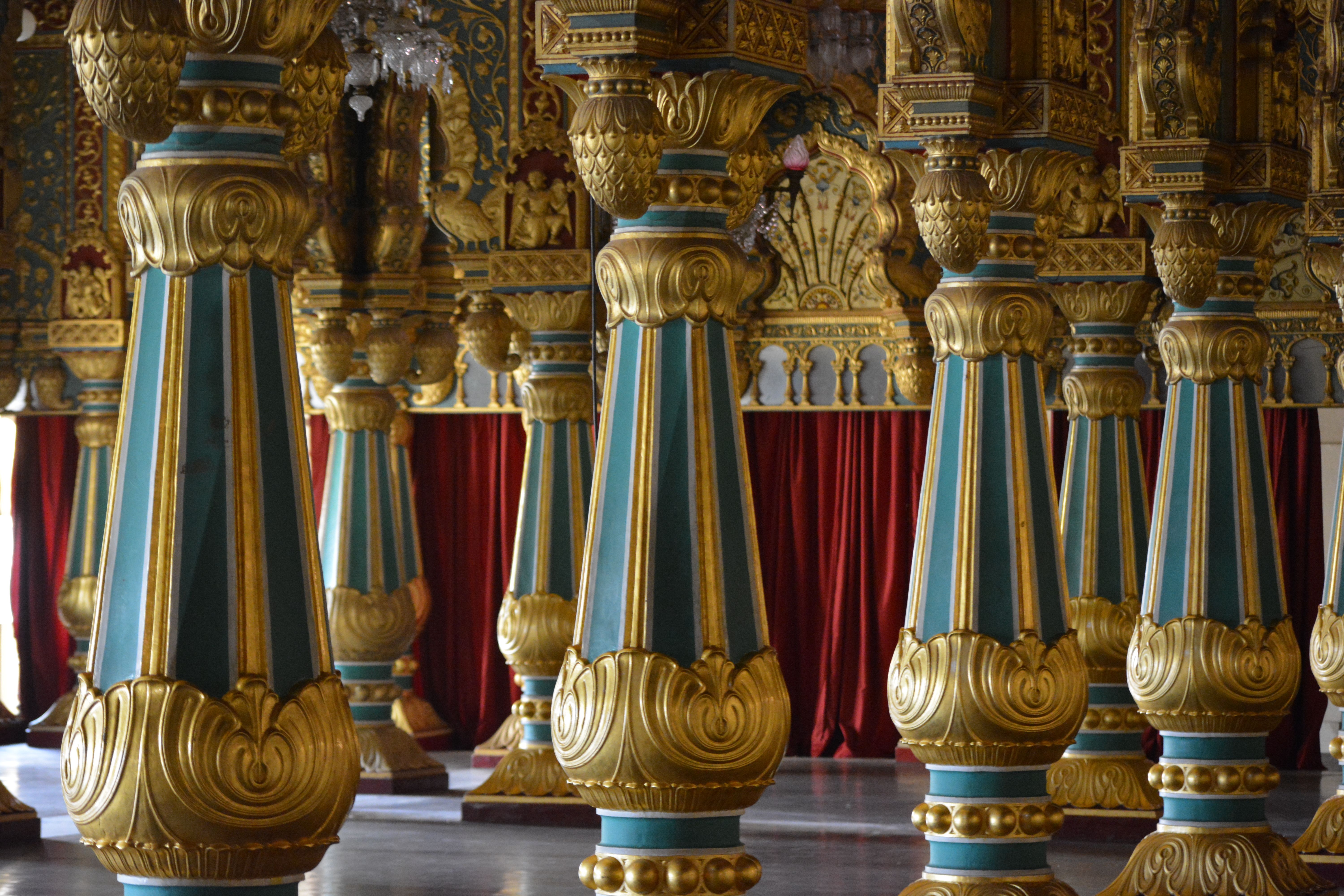 Intricately designed palace columns in gold and blue hues inside a historic royal hall.