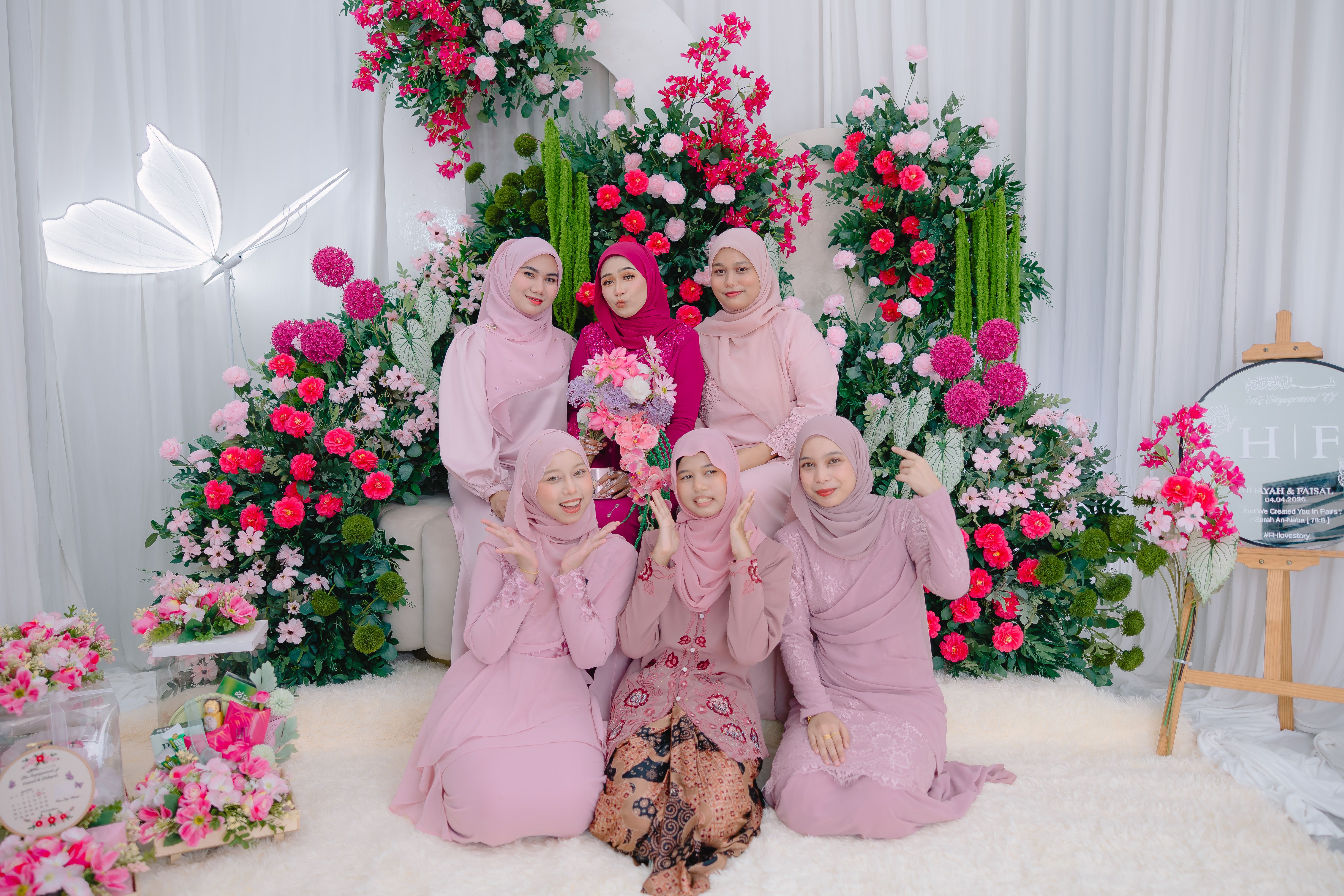 A group of women in beautiful attire pose together at a floral-themed event, showcasing friendship and elegance.