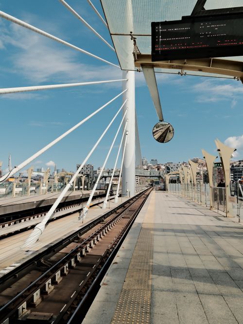 Free A sunny day at a modern urban bridge with railway tracks and cityscape in the background. Stock Photo