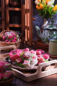 Colorful steamed cakes resembling flowers on a wooden tray, with vibrant tulips in the background. - Fotografer Sidoarjo