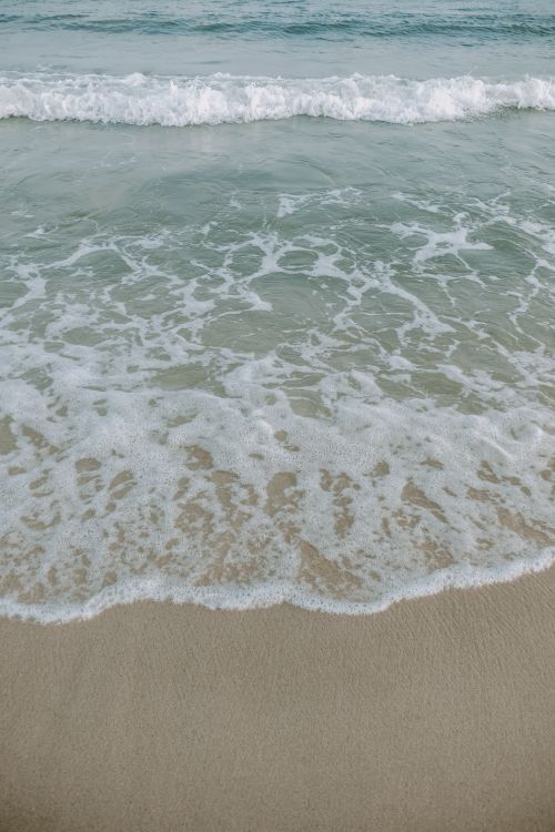 Free Peaceful ocean shore with gentle waves and white sand, capturing a calming and serene beach scene. Stock Photo