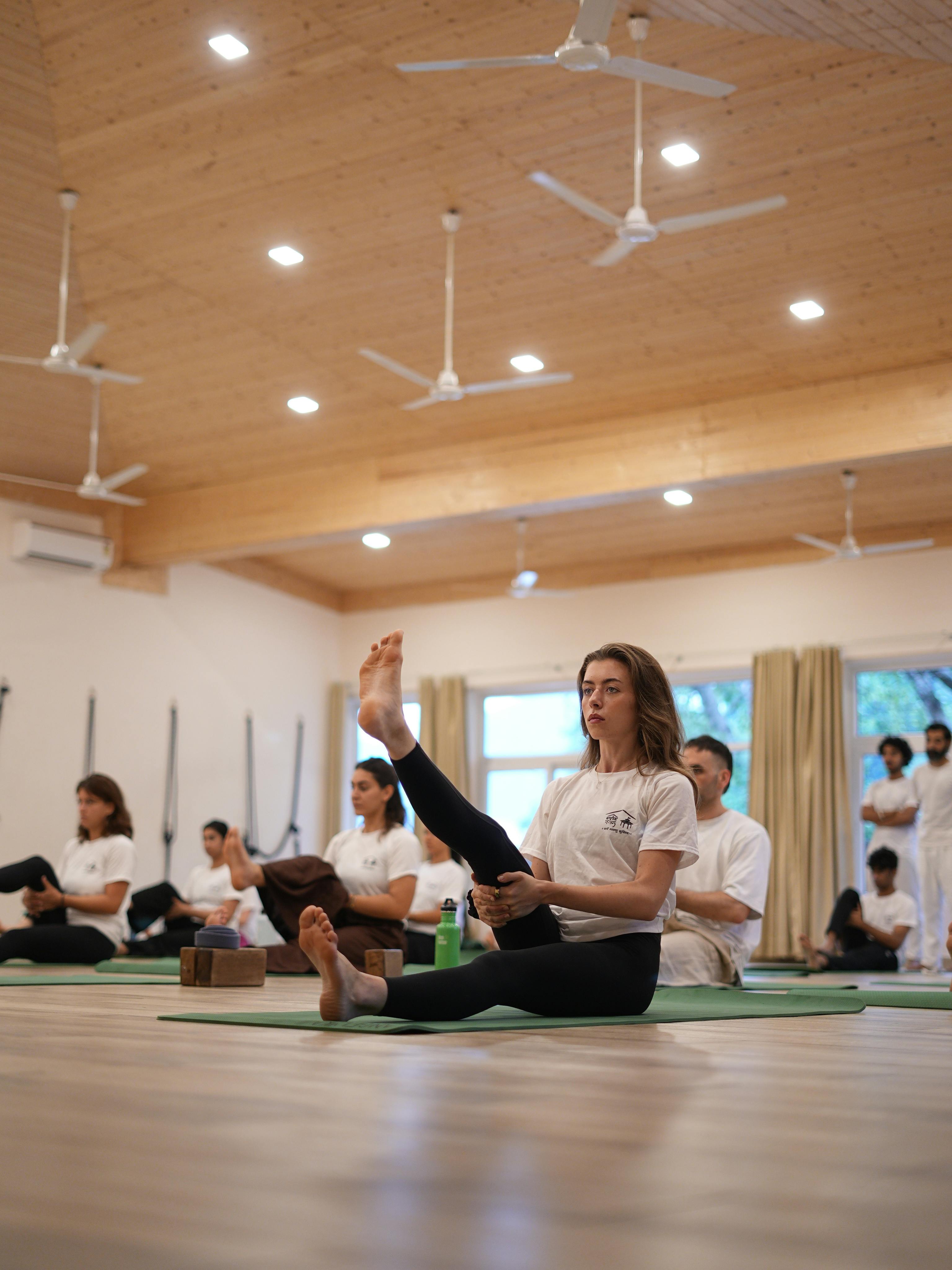 Adults practicing yoga poses indoors in a Rishikesh studio with natural light.