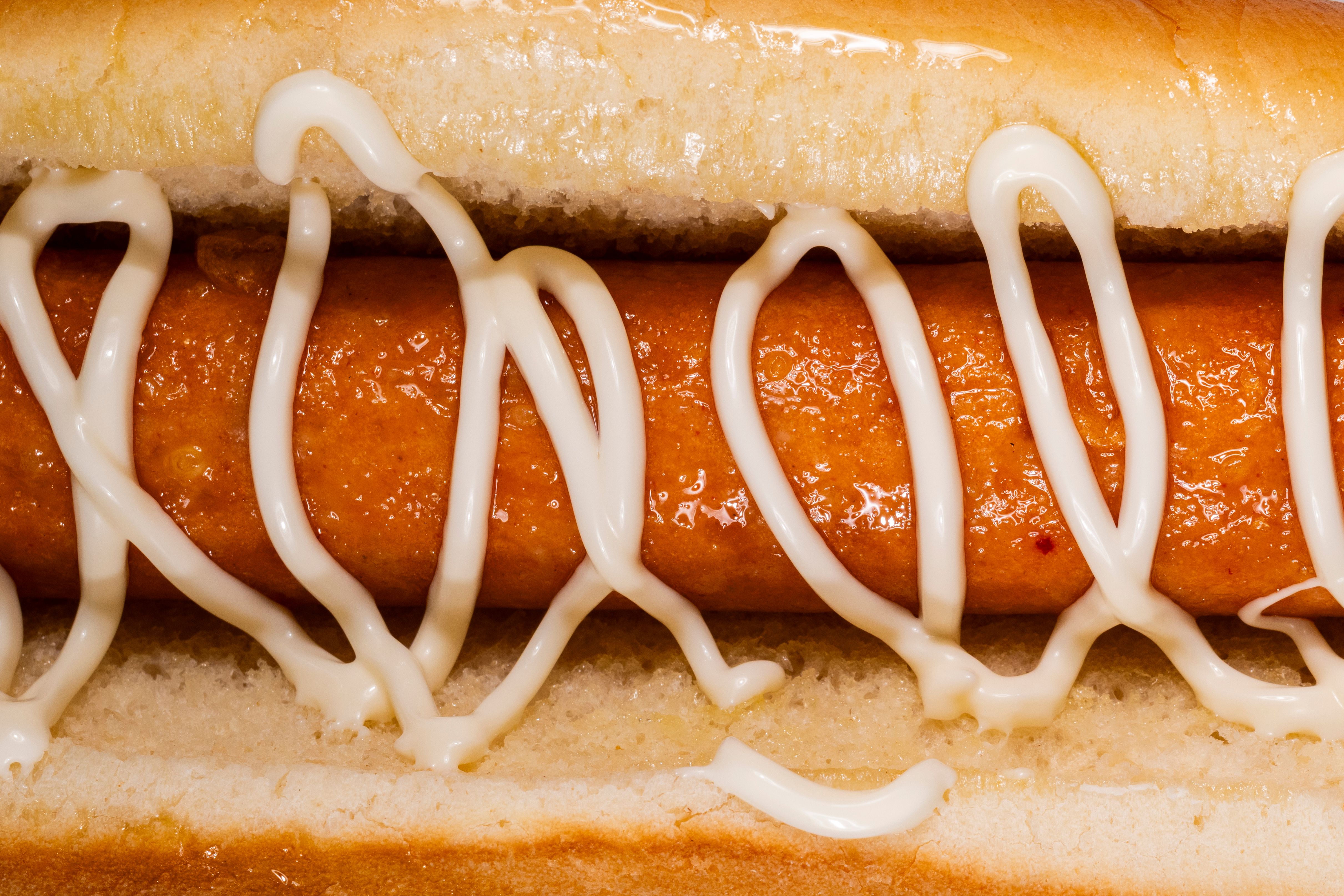 Macro shot of a delicious hotdog with zigzag mayonnaise topping, perfect for fast food themes.
