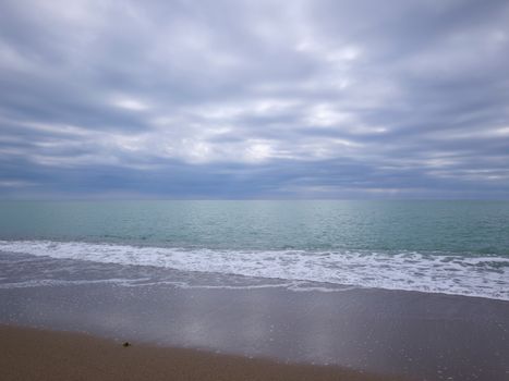 Peaceful beach scene with a calming wave and cloudy sky, ideal for relaxation.