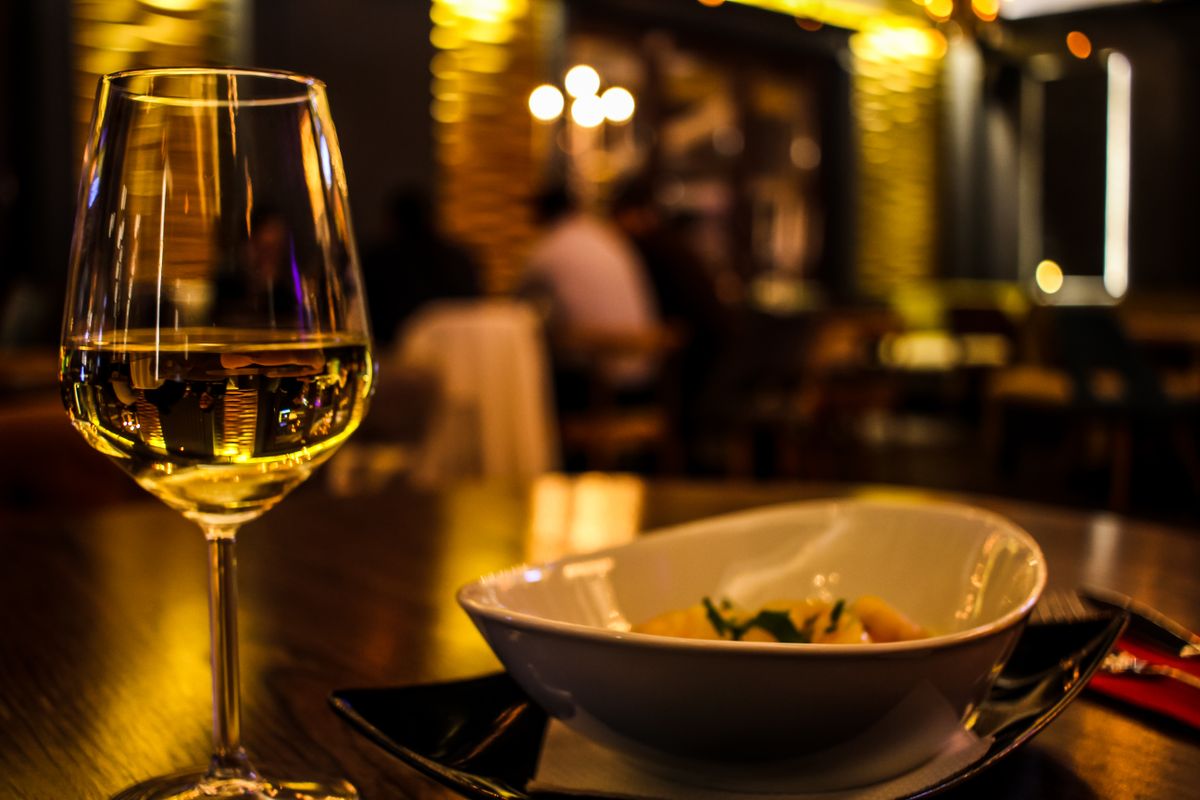 Glass of white wine beside a bowl of curry