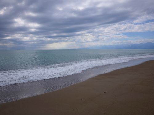 Free Peaceful beach view with gentle waves and a cloudy sky creating a serene atmosphere. Stock Photo