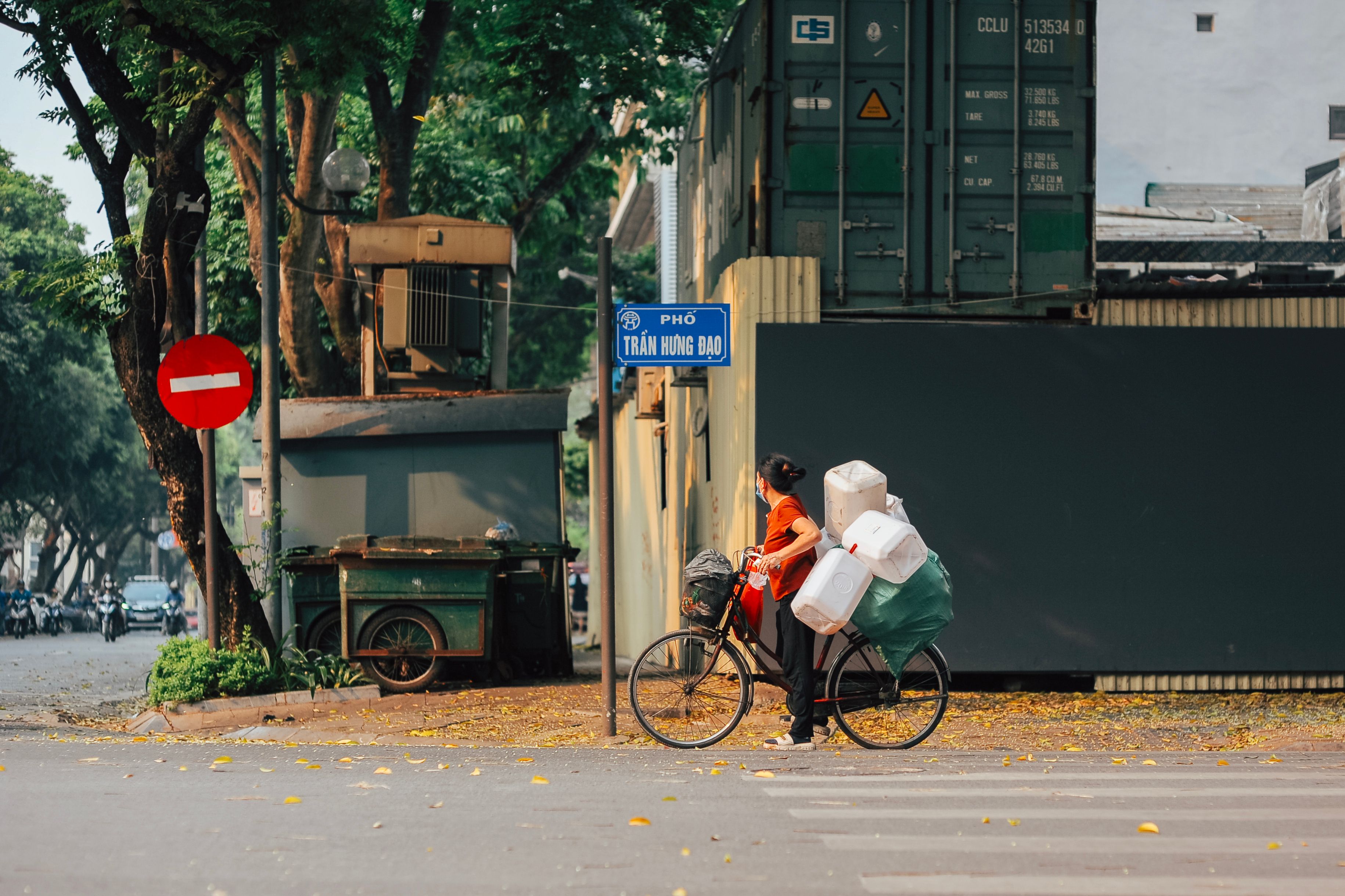 A person on a bicycle carrying large packages waits at an intersection in Hanoi.