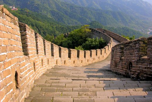 Scenic view of the Great Wall of China winding through lush green mountains.