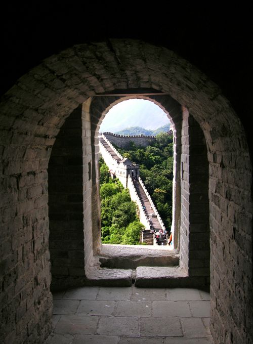 Free Dramatic view of the Great Wall of China framed by arched stone window. Stock Photo