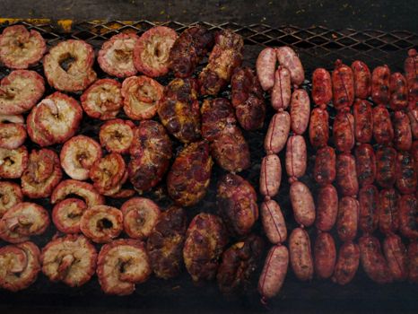 Assorted meats including chorizo and offal grilling on an Argentinian asado in Uribelarrea.