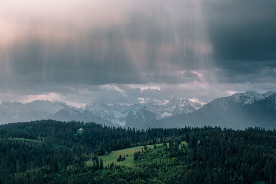 View of the Tatra Mountains during a rainy day with dramatic clouds and lush green forests.