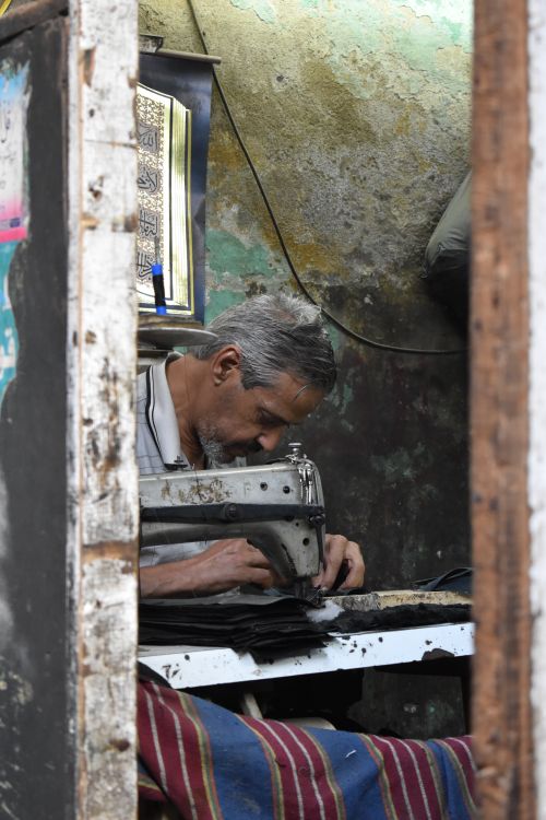 Free An elderly tailor focused on sewing inside a workshop in Cairo, Egypt. Stock Photo