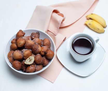 Appetizing banana fritters served with coffee on a chic table setting, perfect for breakfast or brunch.