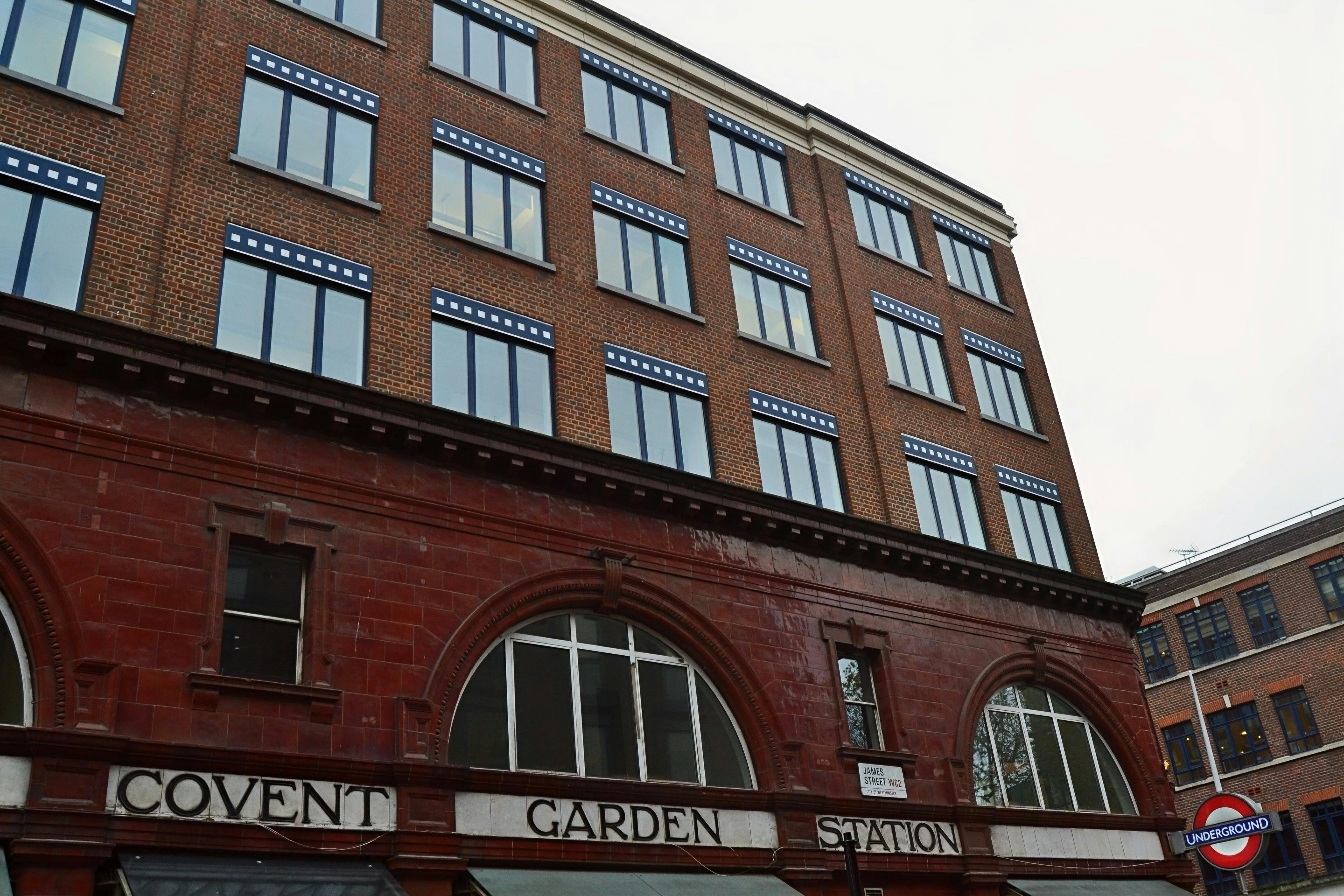 Image of the historic Covent Garden Station in London, showcasing red brick architecture and iconic Underground signage.