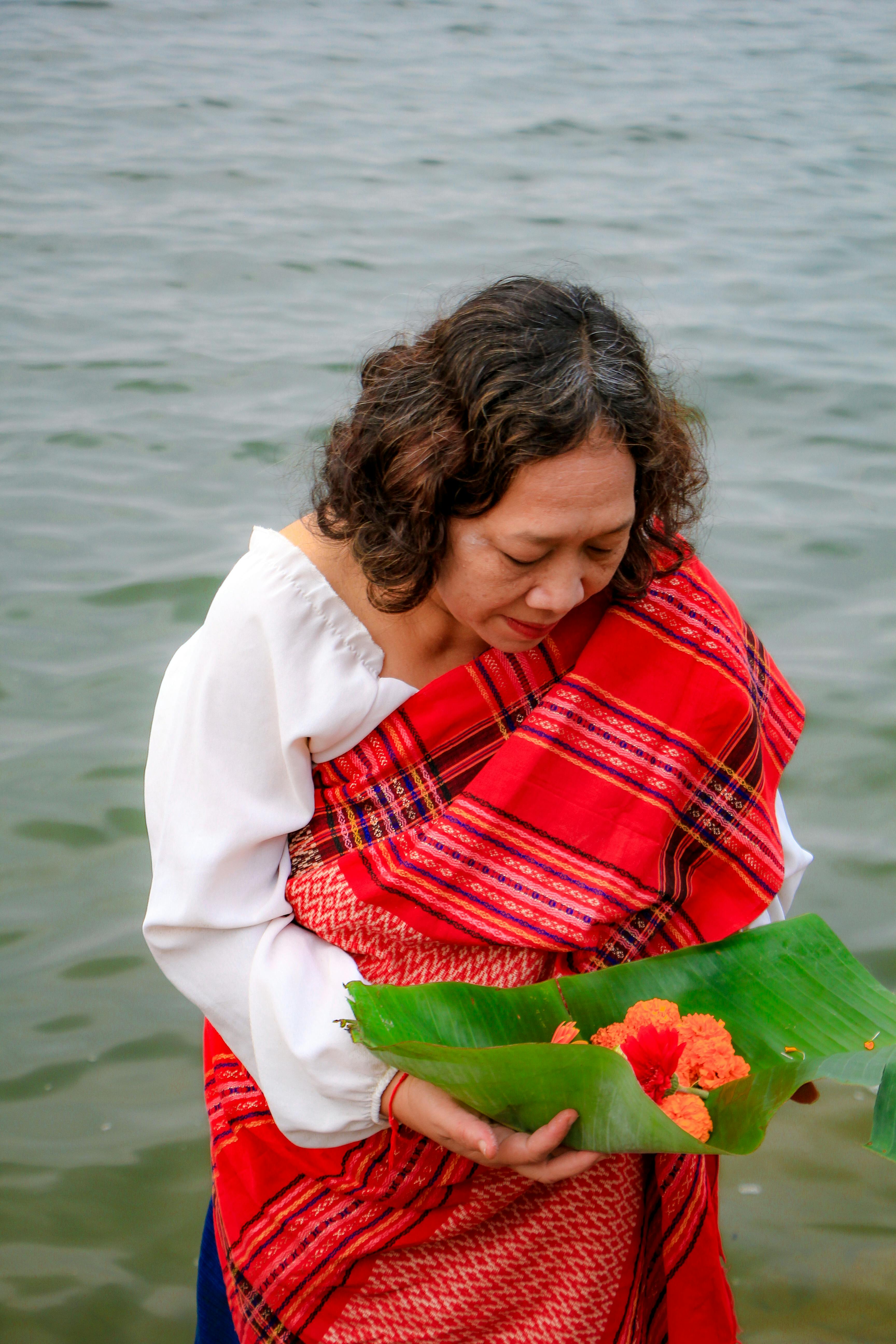 A woman participates in the Phool Biju festival by offering flowers by the river in Rangamati, Bangladesh.