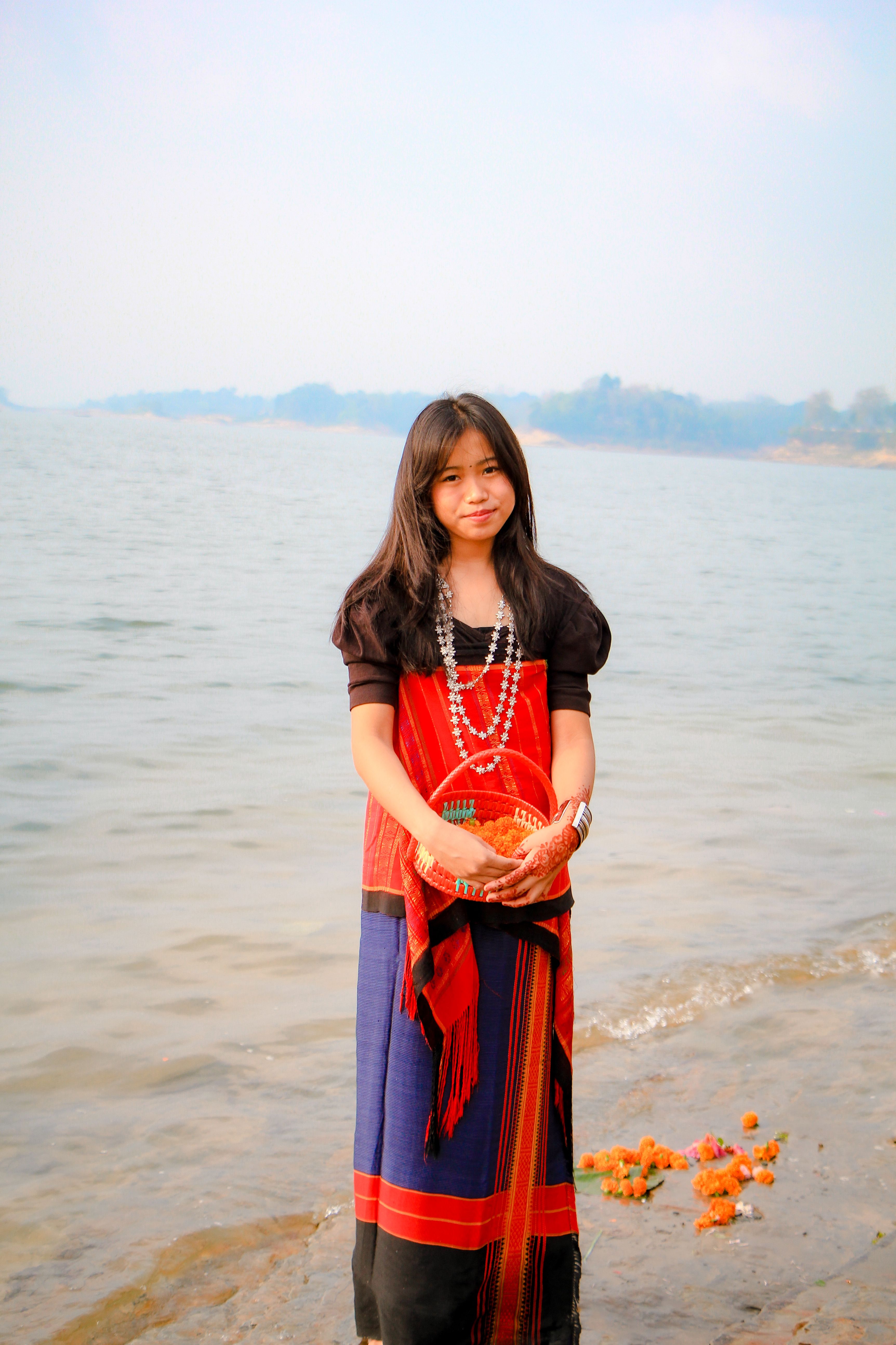 A young girl in traditional dress participating in a cultural festival by the river in Rangamati, Bangladesh.