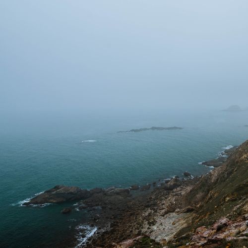 Free A foggy coastline with rocky cliffs and vast ocean view, exuding a moody and serene atmosphere. Stock Photo