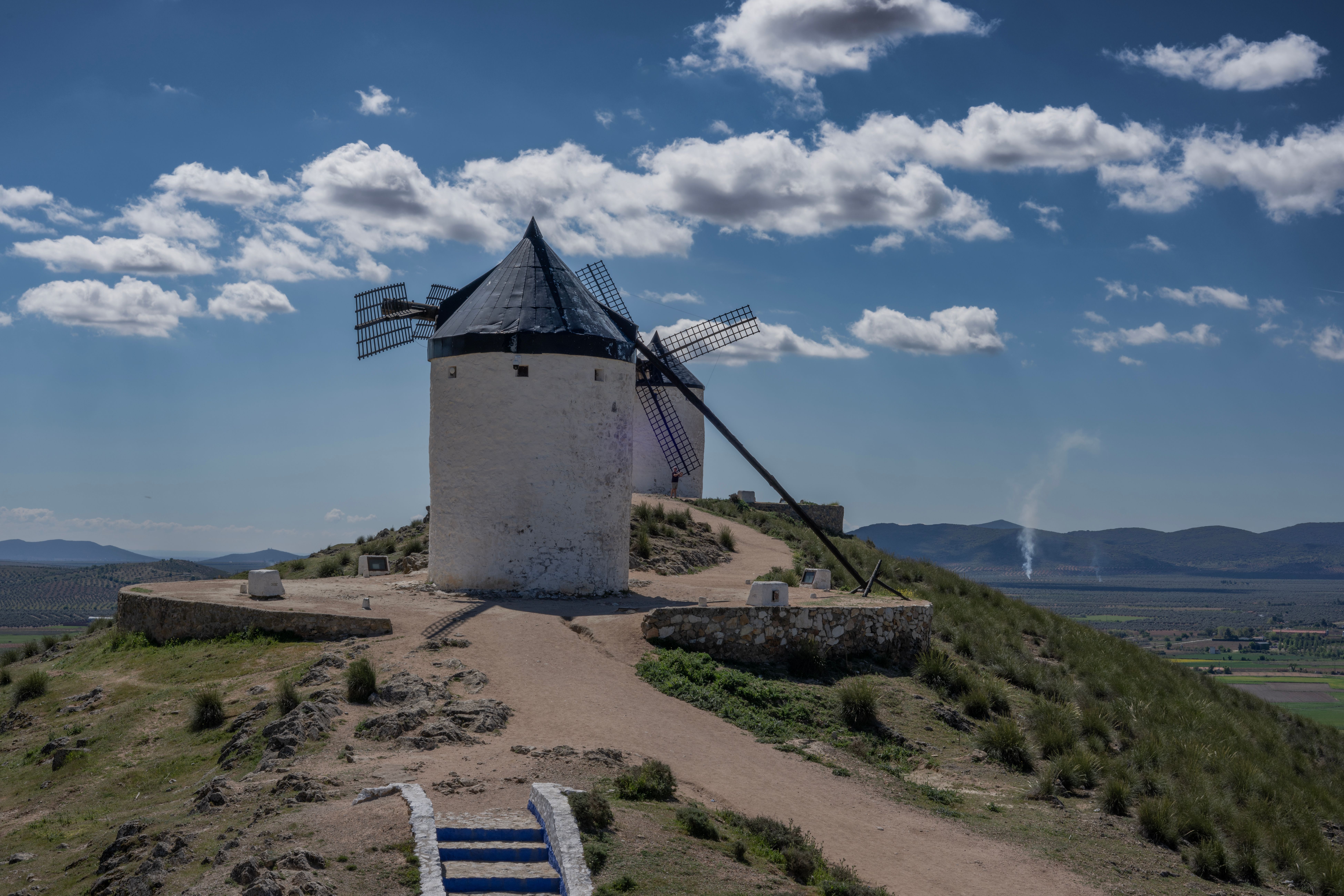 Explore the iconic windmills of Consuegra, Spain, under a beautiful blue sky.