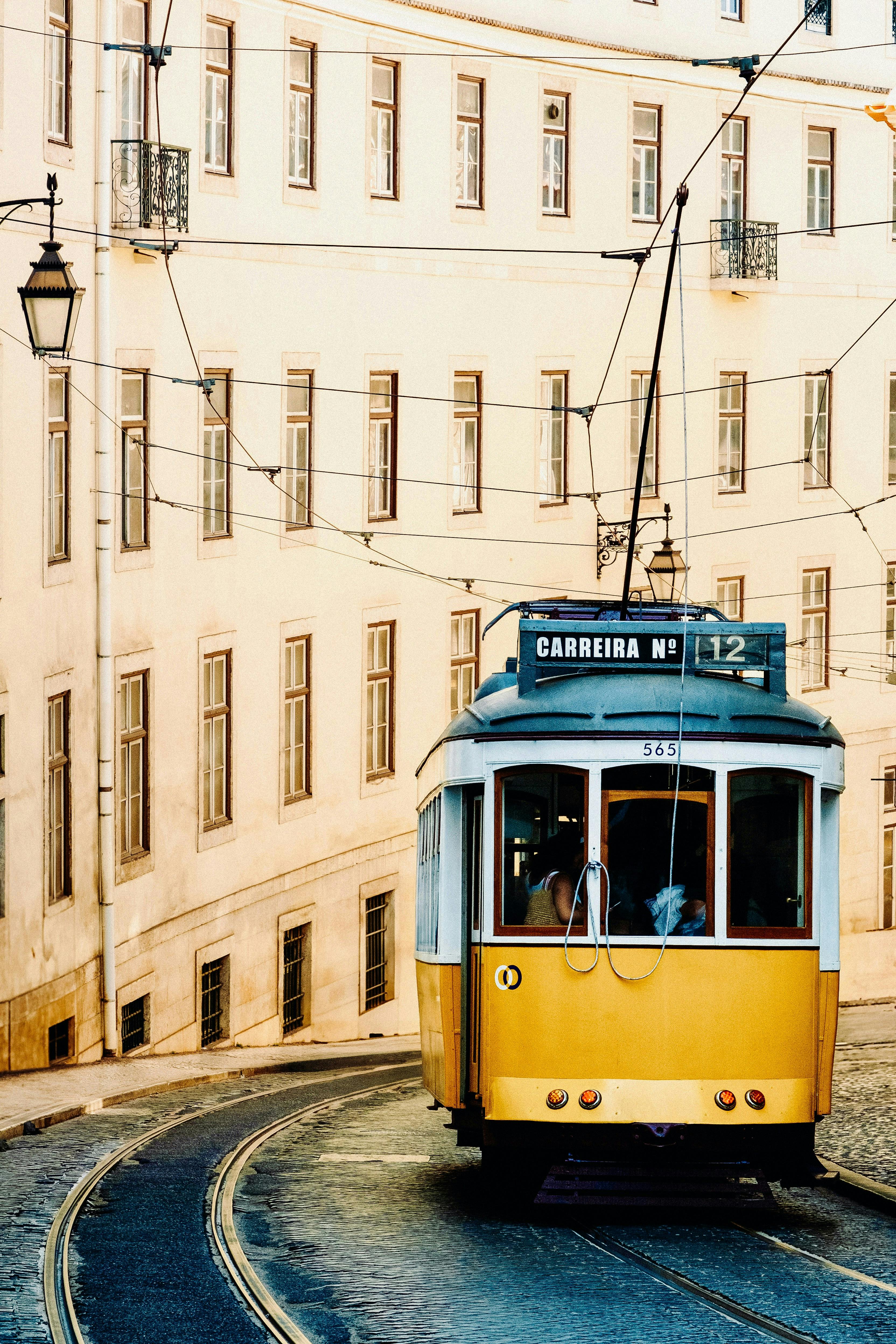 Charming Lisbon tram winds through historic architecture, symbolizing classic city transport.