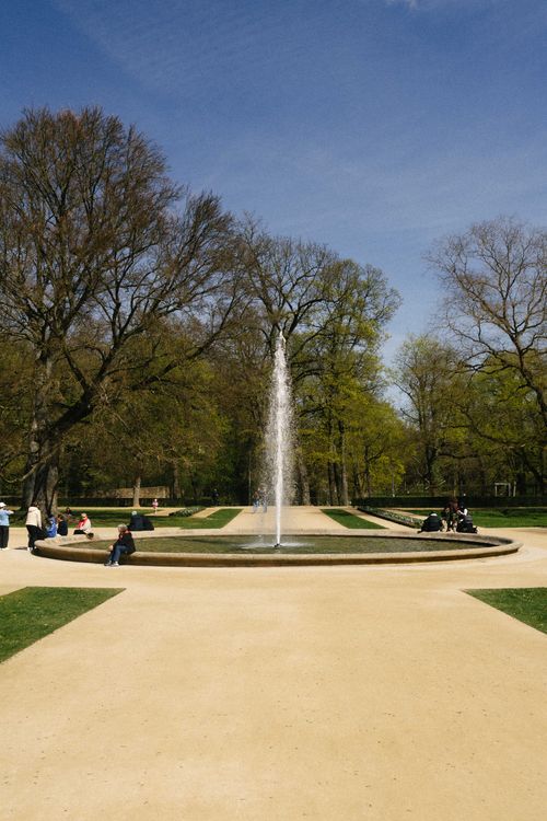 Free A serene fountain in an urban park setting during spring with people enjoying the scenery. Stock Photo