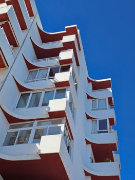 White and red modern architectural building with unique design against a clear blue sky.