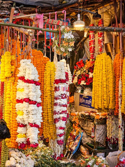 Free Colorful flower garlands hanging in a bustling market in Kolkata, India. Stock Photo
