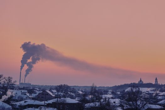 Aerial view of Chernihiv, Ukraine, with chimneys emitting smoke at sunset in winter.