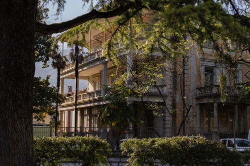 Free A vintage Italian villa with a classic design, nestled amongst dense vegetation and trees. Stock Photo