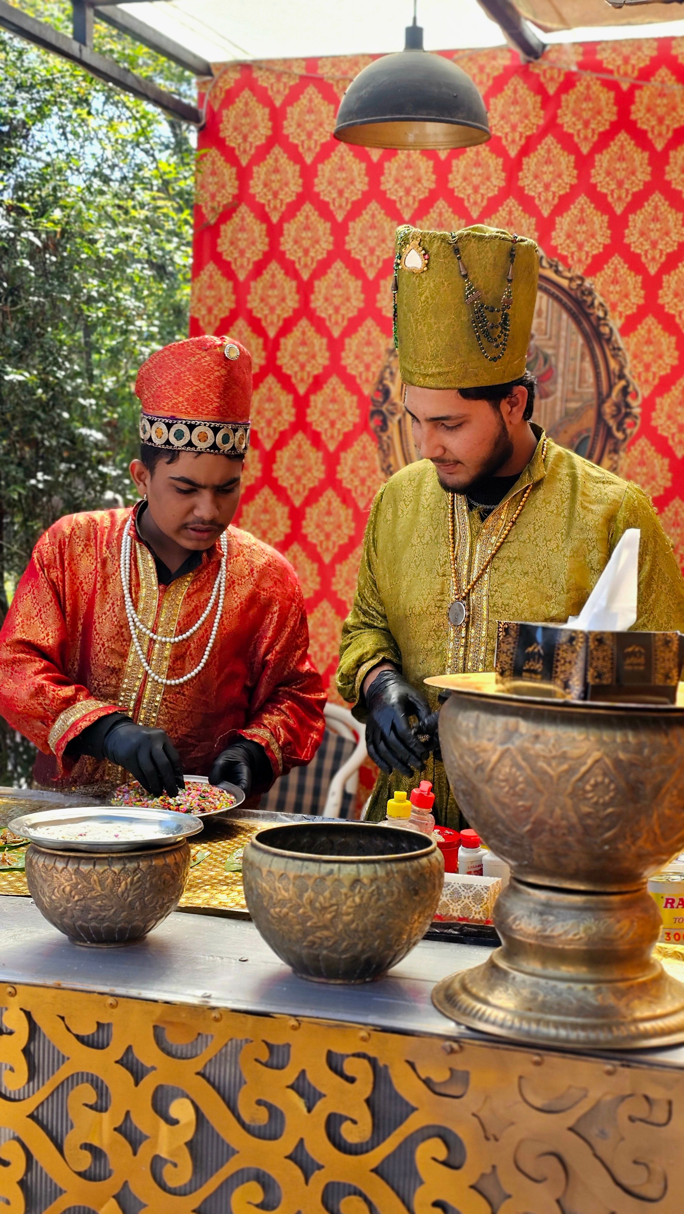 Two men in traditional attire preparing food in an authentic Pakistani setting outdoors.