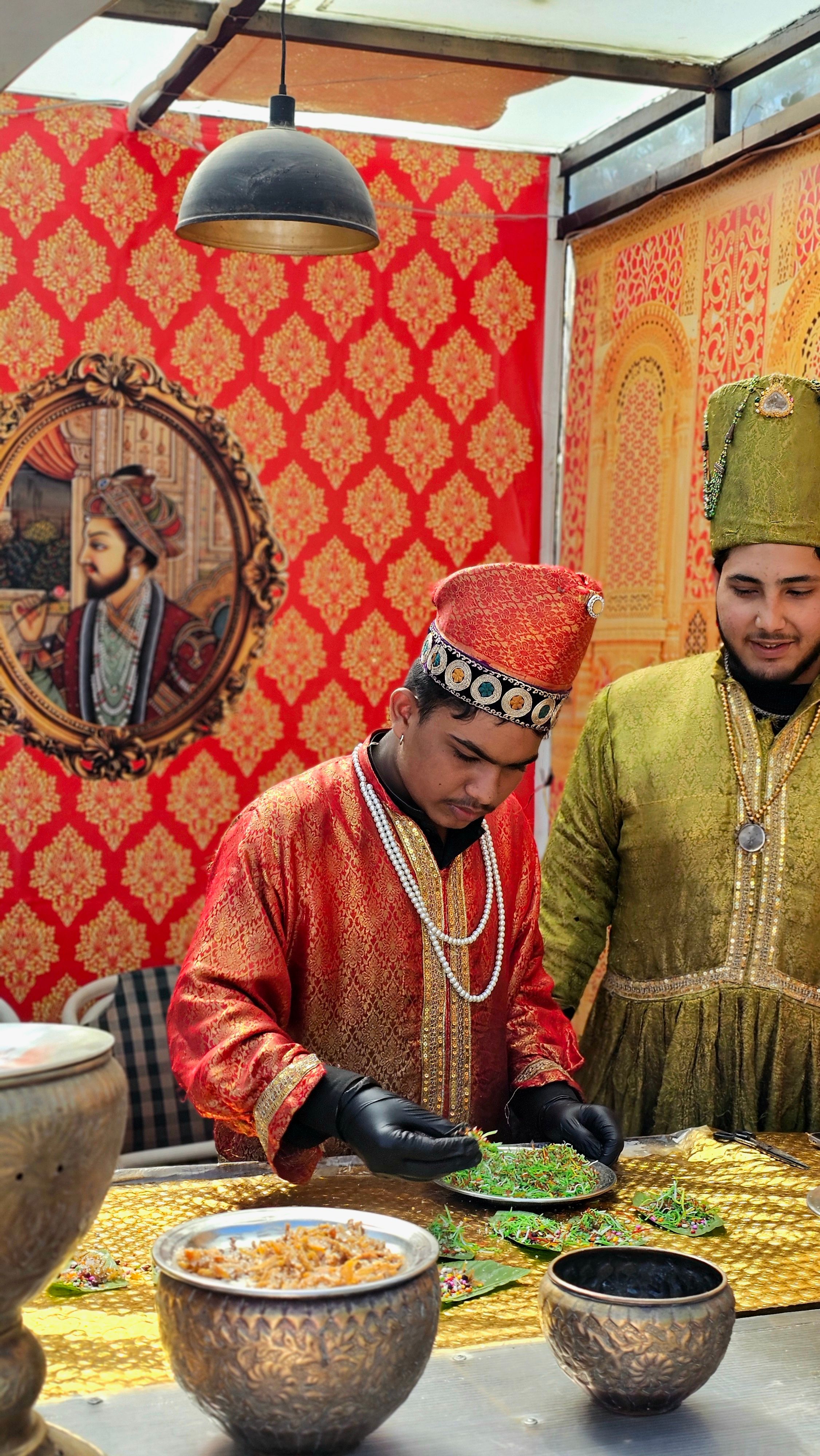 Men in traditional Mughal costumes preparing food in a Pakistan street market setting.
