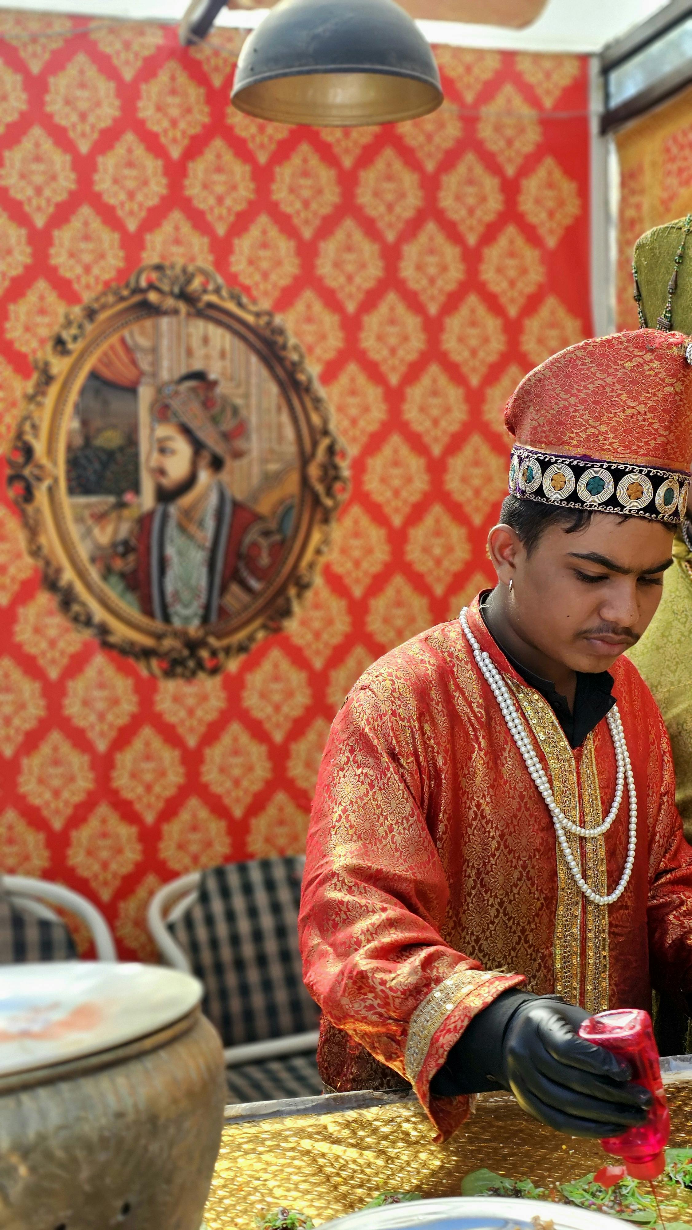 Young man in traditional Mughal attire preparing dish at cultural event in Islamabad, Pakistan.