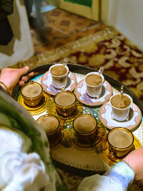 Free Person serving coffee in ornate cups on a decorative tray indoors. Stock Photo